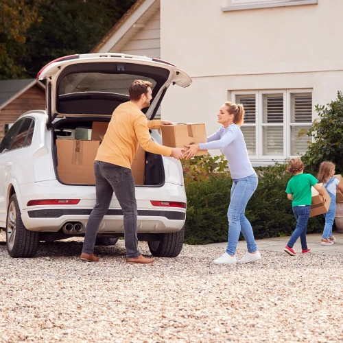 Family carrying boxes from car to new home